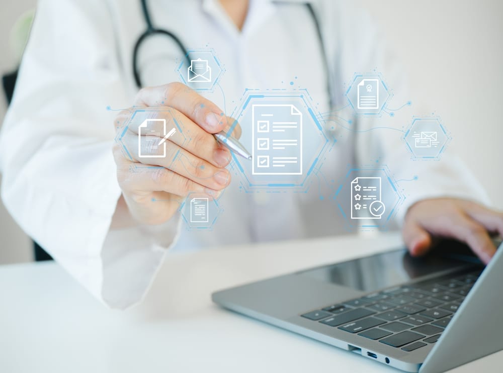 Digital icons representing medical documents overlaid on an image of a healthcare worker typing on a laptop.